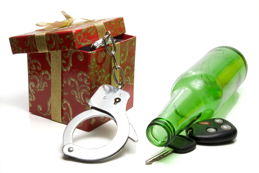 a small gift box with handcuffs hanging out next to a glass green beer bottle with car keys underneath