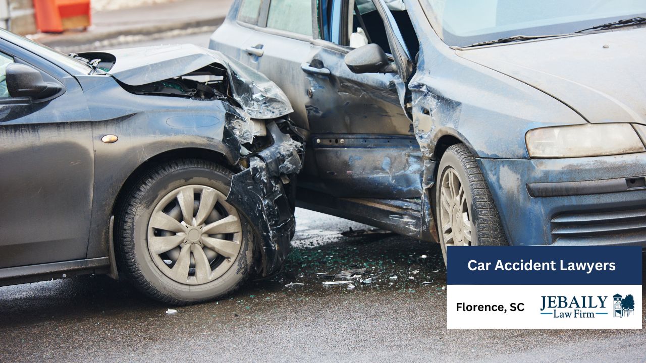 The car on the left, dark gray or black, has significant front-end damage. The hood is dented and crumpled, and the front bumper and surrounding areas are severely damaged. The front wheel well and the car's frame structure are exposed.
