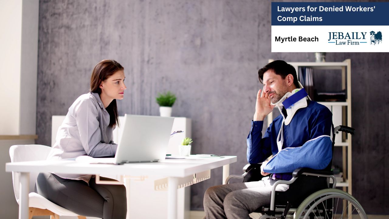 A man and a woman are sitting at a table, working on a laptop. The setting appears to be an office space, likely related to their profession as lawyers. The scene is from Myrtle Beach, associated with the JEBAILY law firm