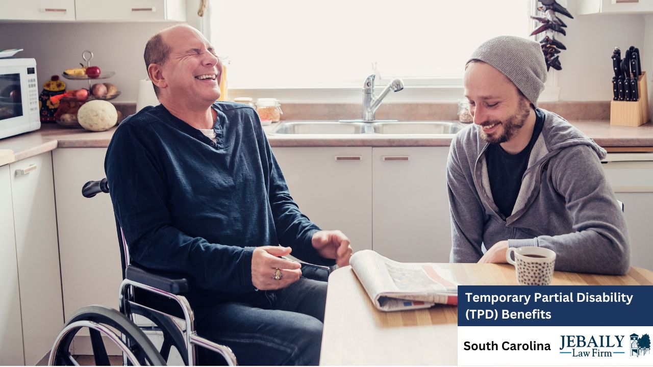 Two men, one in a wheelchair, sit at a kitchen table reading a newspaper. One holds coffee. Text reads 'Temporary Partial Disability (TPD) Benefits' with JEBAILY law firm and South Carolina logo.
