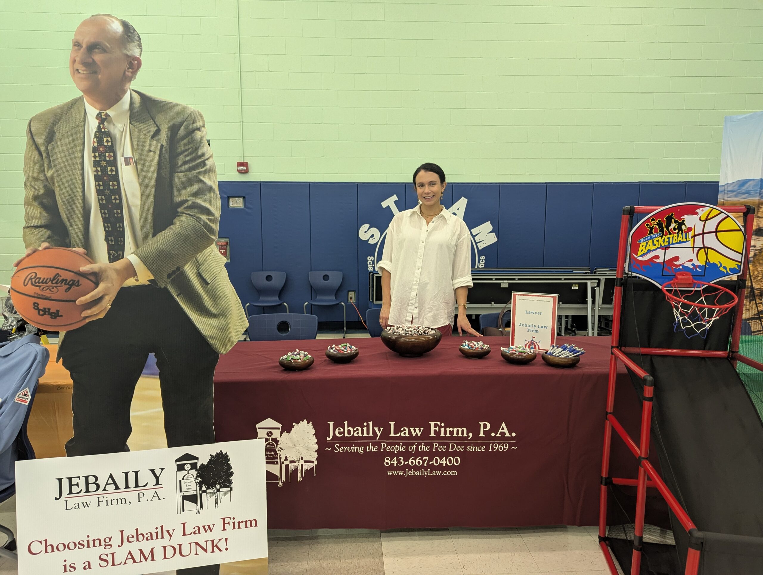 Attorney Kayla Jebaily Adams stands behind Jebaily Law Firm's table at Carver Elementary's Career Day event