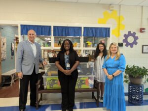 Jebaily Law Firm staff and Carver Elementary staff stand and pose with donation items in school hallway