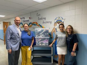 George Jebaily stands with Kayla Jebaily Adams and recipients of clothing and shoe donation in elementary school hallway