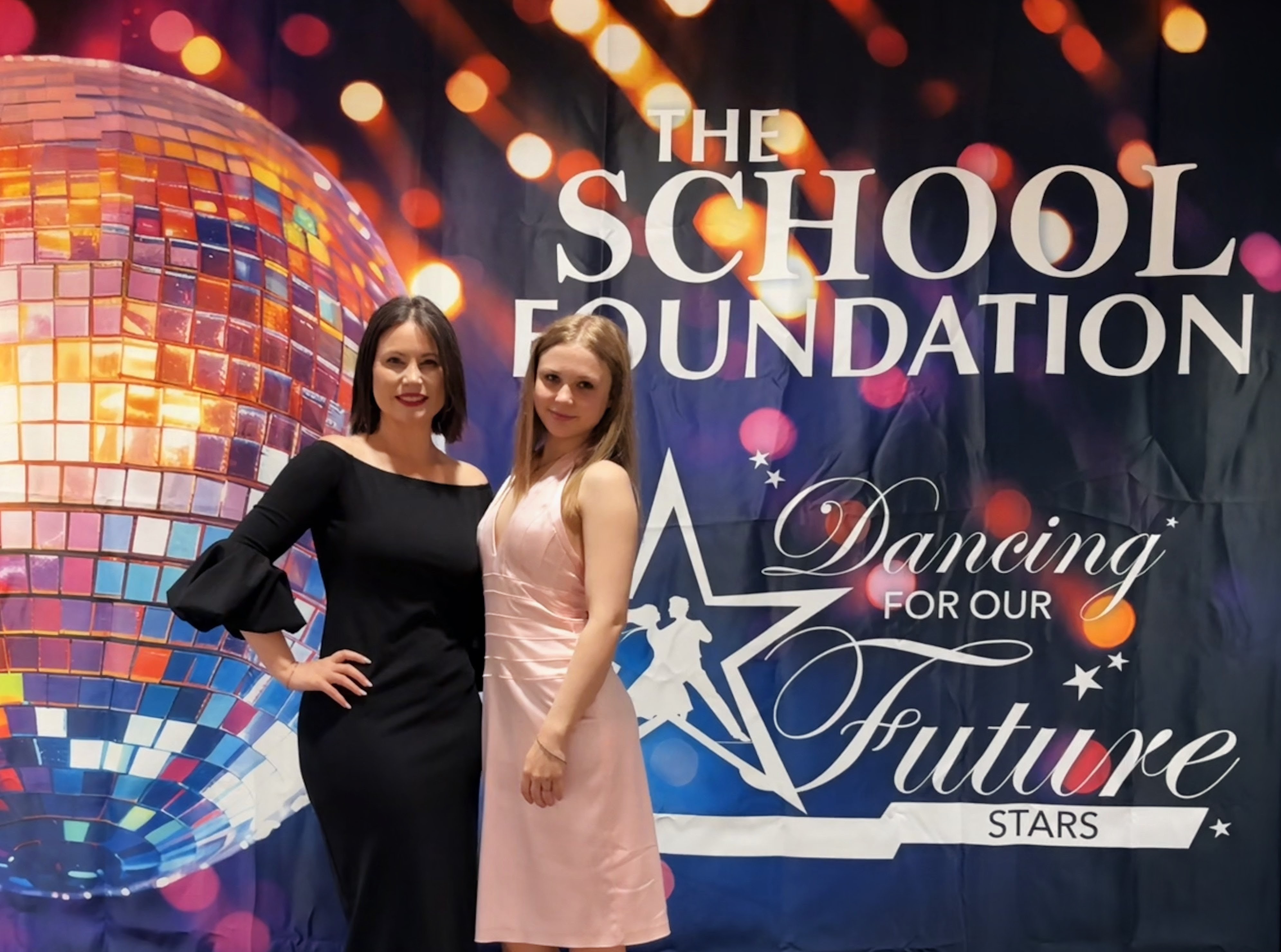 Two people standing in front of The School Foundation event banner in formal wear.