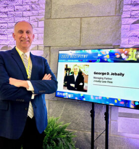 George Jebaily stands next to a sign recognizing him for making top 50 Pee Dee people